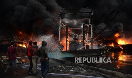 Sejumlah petugas pemadam kebakaran dibantu warga berusaha memadamkan kapal yang terbakar di Pelabuhan Muara Baru, Jakarta, Sabtu (23/2).