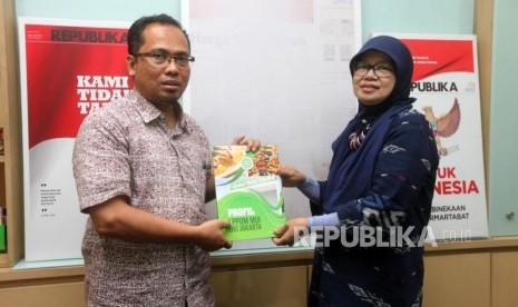 Wakil Direktur Pembina Daerah LPPOM MUI Osmena (kanan) menyerahkan buku kepada Wakil Pemimpin Redaksi Nur Hasan Murtiaji (kiri) saat kunjungan ke Kantor Harian Republika, Jakarta, Jumat (19/10).