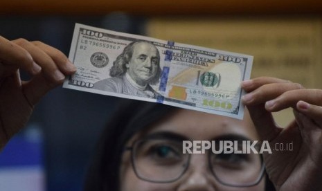 Petugas memeriksa mata uang dolar AS di salah satu tempat penukaran uang di Jakarta, Jumat (9/11).