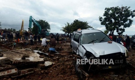 Sejumlah warga melihat alat berat melakukan evakuasi bangunan yang terdampak tsunami di Desa Way Muli, Kalianda, Lampung Selatan, Senin (24/12).