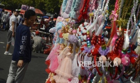 Warga saat akan membeli aksesoris yang dijual pedagang kaki lima pada hari bebas kendaraan bermotor di kawasan Bundaran HI, Jakarta, Ahad (25/8).