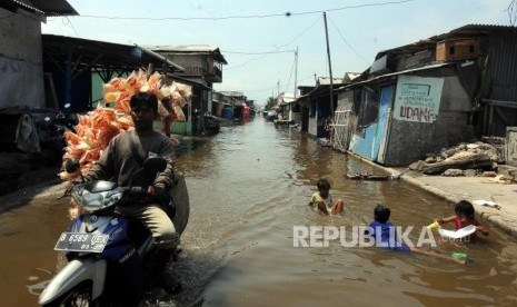 Anak-anak bermain saat terjadi banjir rob yang menggenangi kawasan Muara Angke, Jakarta Utara, Rabu (3/1).