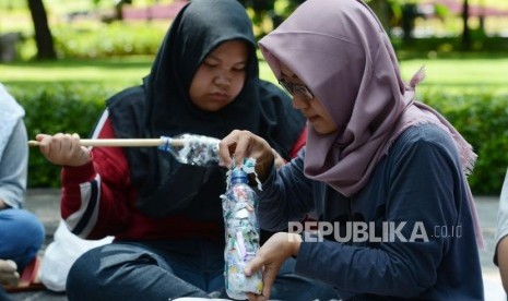 Sejumlah anggota Komunitas Jakarta Ecobrick memadatkan sampah plastik ke dalam botol di Taman Suropati, Jakarta, Ahad (16/12).