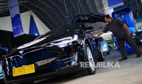 TAKSI LISTRIK. Awak armada e-Taxi Silver Bird membuka pintu penumpang mobil Tesla X75 di Port Charging Bluebird di Jakarta, Senin (22/4).