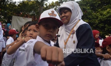 Seorang guru merapihkan barisan pelajar ada hari pertama masuk sekolah di SDN Pejaten Barat  01 Pagi  , Jakarta, Senin (16/7).