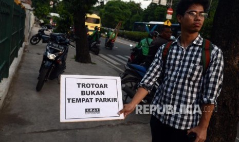 Sejumlah aktivis Koalisi Pejalan Kaki saat melakukan aksi Tamasya Trotoar di Jalan I Gusti Ngurah Rai, Klender, Jakarta Timur, Jumat (7/12).