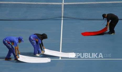 Pengeringan Manual Lapangan Tenis. Volunteer mengeringkan lapangan tenis secara manual saat pertandingan pada cabang tenis Asian Games 2018 di Komllek Olahaga Jakabaring, Palembang, Jumat (24/8).