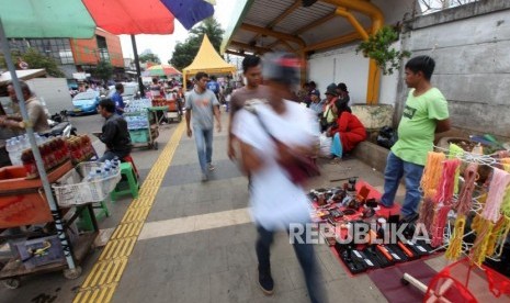 Warga melintasi para pedagang kali lima (PKL) di trotoar kawasan Tanah Abang, Jakarta, Kamis (14/12).