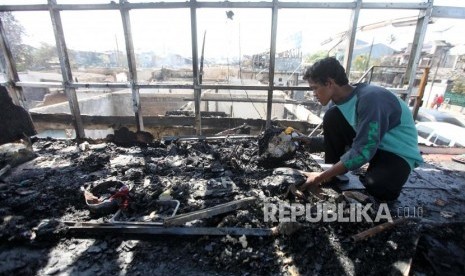 Warga membersihkan puing-puing bangunan pasca kebakaran di Kawasan Perumahan Taman Kota, Jakarta, Jumat (30/3).