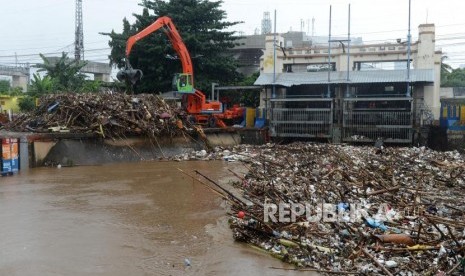 Pekerja menggunakan alat berat mengangkut sampah yang mengalir ke Pintu Air Manggarai. BPBD menyebutkan hingga kini belum ada pintu air di DKI berstatus awas