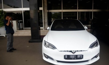 Jurnalis mengambil gambar mobil listrik Tesla yang terparkir di depan Gedung Nusantara III, Kompleks Parlemen, Jakarta, Selasa (3/7).