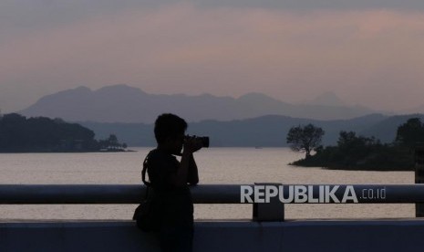 Ikan Mati di Waduk Jangari Cianjur Capai 200 Ton. Pengunjung memotret salah satu sudut Waduk Cirata di Pembangkit Listrik Tenaga Air Cirata, Kabupaten Purwakarta.