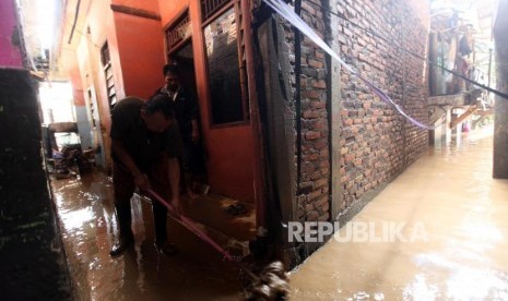 Warga membersihkan rumahnya dari lumpur pasca banjir di Kawasan Rawajati, Jakarta, Selasa (6/2).