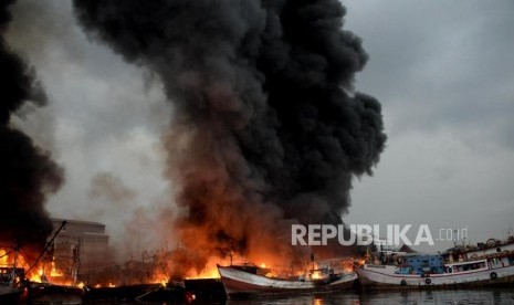 Sejumlah petugas pemadam kebakaran dibantu warga berusaha memadamkan kapal yang terbakar di Pelabuhan Muara Baru, Jakarta, Sabtu (23/2).