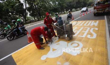 Pekerja mengecat jalur kuning khusus sepeda motor di Kawasan Jalan Merdeka Barat, Jakarta, Rabu (17/1).