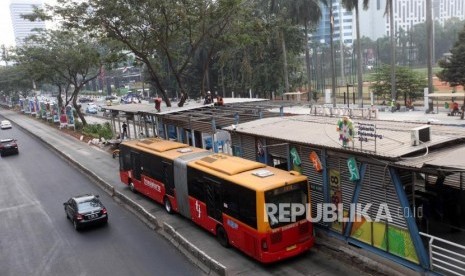 Bus Transjakarta melintas saat pekerja menyelesaikan perluasan Halte Transjakarta Gelora Bung Karno di Kawasan Sudirman, Jakarta, Kamis (19/7).