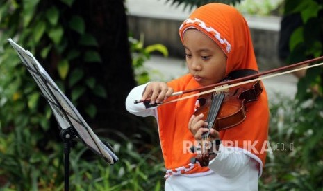 Anak-anak belajar memainkan alat musik biola di Taman Suropati, Menteng, Jakarta, Ahad (15/4).