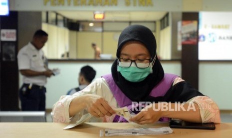 Warga mempersiapkan surat-surat saat melakukan pembayaran pajak kendaraan bermotor di Kantor Samsat Polda Metro Jaya, Jakarta, Jumat (16/11).