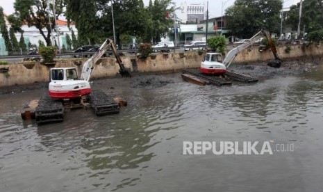 Petugas menggunakan alat berat mengeruk endapan sampah bercampur lumpur di aliran sungai Ciliwung, Kawasan Pasar Baru, Jakarta, Selasa (13/2).