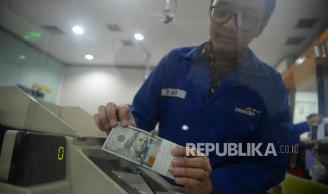 Karyawan menghitung tumpukan uang dolar Amerika Serikat di Cash Center Bank Mandiri, Jakarta, Senin (23/7).