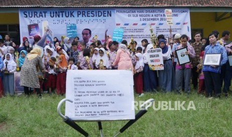 Para pelajar membawa piala dan poster bersiap untuk berfoto bersama usai membuat surat untuk Presiden Joko Widodo (Jokowi) pada saat peringatan Hari Disabilitas Internasional, di Sekolah Luar Biasa Negeri (SLBN) A, Kota Bandung, Kamis (29/11).