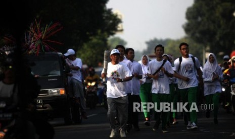 Warga membawa replika obor Asian Games saat pawai Festival Jelang Obor Asian Games 2018 di Kawasan Pasar Minggu, Jakarta, Ahad (1/7).