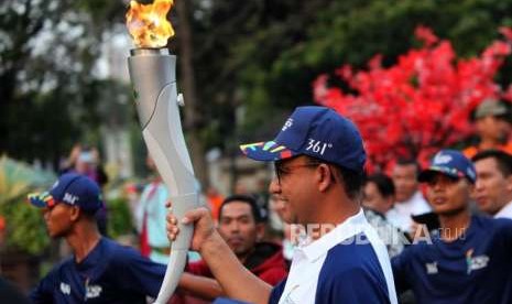 Gubernur DKI Jakarta Anies Baswedan membawa obor saat Torch Relay Asian Games 2018 di Balai Kota, Jakarta, Rabu (15/8).