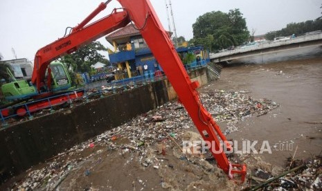 Petugas menggunakan alat berat mengangkut sampah di Pintu air Manggarai, Jakarta, Senin (5/2).