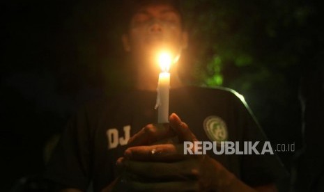 Seorang suporter memegang lilin sekaligus berdoa saat aksi solidaritas terkait aksi tragedi teror bom di Surabaya dan Siduarjo di Taman Suropati, Jakarta, Senin (14/5).