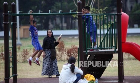 Seorang anak bermain didampingi orang tuanya. Ilustrasi