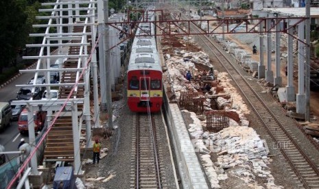 Kereta commuter line melintas disamping area pembangunan proyek peron Stasiun Buaran di Jakarta, Kamis (4/1).