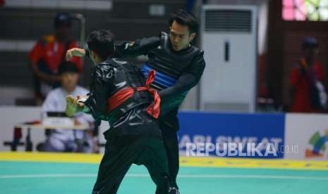 Pesilat Indonesia Komang Harik Adi Putra (pita biru) bertanding melawan Pesilat Singapura Muhammad Shakir Juanda pada babak perempat final cabang pencak silat putra kelas E 65-70 kg Asian Games 2018 di Padepokan Pencak Silat TMII, Jakarta, Jumat (24/8).