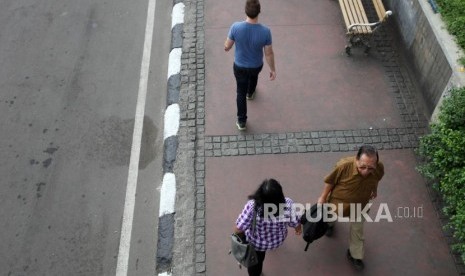 Sejumlah pekerja kantor berjalan di Trotoar Kawasan MH Thamrin, Jakarta, Rabu (7/3).