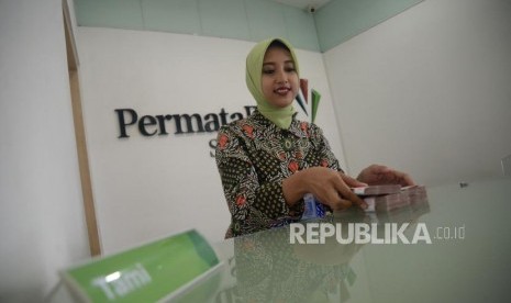 Petugas melayani transaksi nasabah di kantor layanan Permata Bank.