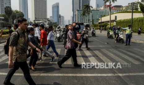 Sejumlah karyawan menggunakan baju batik saat melintasi pelican crossing di kawasan Bundaran HI, Jakarta, Rabu (2/10).