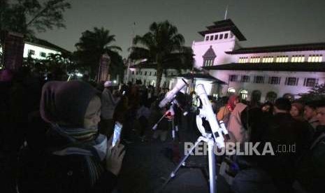 Masyarakat antere melihat planet mars dan bulan yang sedang dalam posisi terdekat dengan bumi melalui teropong pada acara Dark Sky Night atau Malam Langit Gelap yang bertepatan dengan Peringatan Hari Antariksa Nasional, di halaman Gedung Sate, Kota Bandung, Senin (6/8).