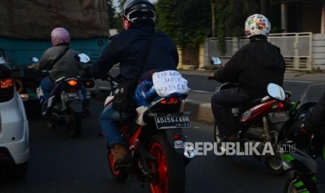 pemudik kendaraan roda dua memasang tulisan di motor saat mudik ke jalur pantura, Cikampek, Jawa Barat, Sabtu (9/6).