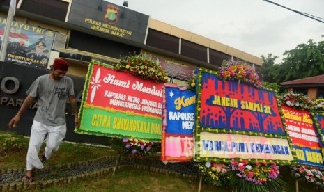 Pekerja saat memasang karangan bunga di depan Mapolres Metro Jakarta Barat, Kamis (22/11).