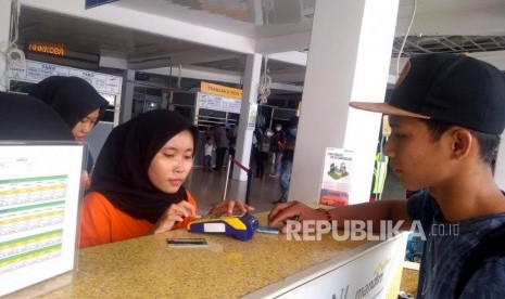 Penumpang melakukan isi ulang (top-up) uang elektronik untuk membeli tiket kapal di Pelabuhan Merak, Banten, Jumat, (3/5).