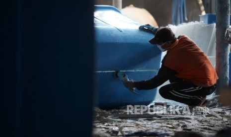 Pekerja menyelesaikan pembuatan septic tank dan toilet portabel di industri rumahan.