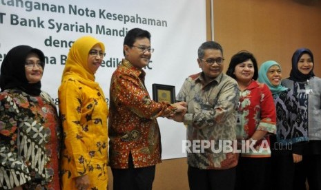 Direktur Wholesale Banking Mandiri Syariah Kusman Yandi (empat kanan) bersama Direktur Utama PT Pertamina Bina Medika (PT PBM) DR Dany Amrul Ichdan (ketiga kiri) bersama jajaran usai melakukan penandatanganan nota kesepahaman di Jakarta, Selasa (28/11).