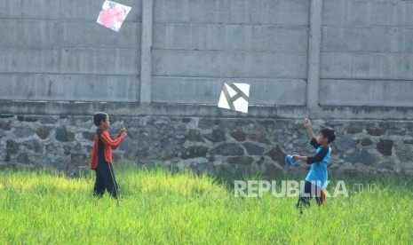 Dua orang anak bermain layangan 