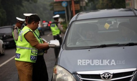 Petugas gabungan melakukan penertiban pajak kendaraan bermotor saat razia pengesahan Surat Tanda Nomor Kendaraan (STNK) di Jalan Raya Kalibata, Jakarta Selatan, Selasa (24/4).