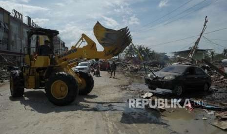 Petugas mengevakuasi mobil yang rusak di Pantai Talise, Palu, Sulawesi Tengah, Ahad (7/10).