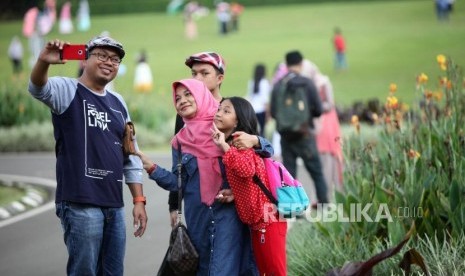 Warga berfoto selfie saat berwisata di Kebun Raya Bogor, Jawa Barat, Sabtu (23/12).