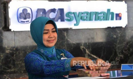 Karyawan melayani transaksi setoran nasabah di BCA Syariah (ilustrasi).