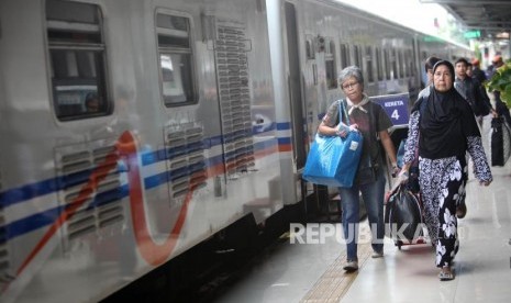 Penumpang berjalan saat akan menaiki kereta api di Stasiun Pasar Senen, Jakarta, Selasa (26/12).