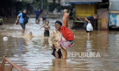 Warga melintasi genangan saat banjir melanda ruas jalan Jatinegara Barat, Jakarta, Selasa(6/2).