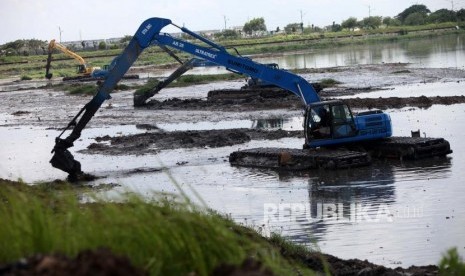 Pekerja mengoperasikan alat berat untuk mengeruk dasar sungai yang  dipenuhi lumpur di Banji Kanal Timur, Jakarta, Jumat (27/4).