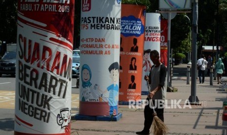 Target Partisipan Pemilu 2019. Petugas menyapu di dekat spanduk sosialisasi Pemilu 2019 di Jalan Medan Merdeka Barat, Gambir, Jakarta, Senin (25/2).